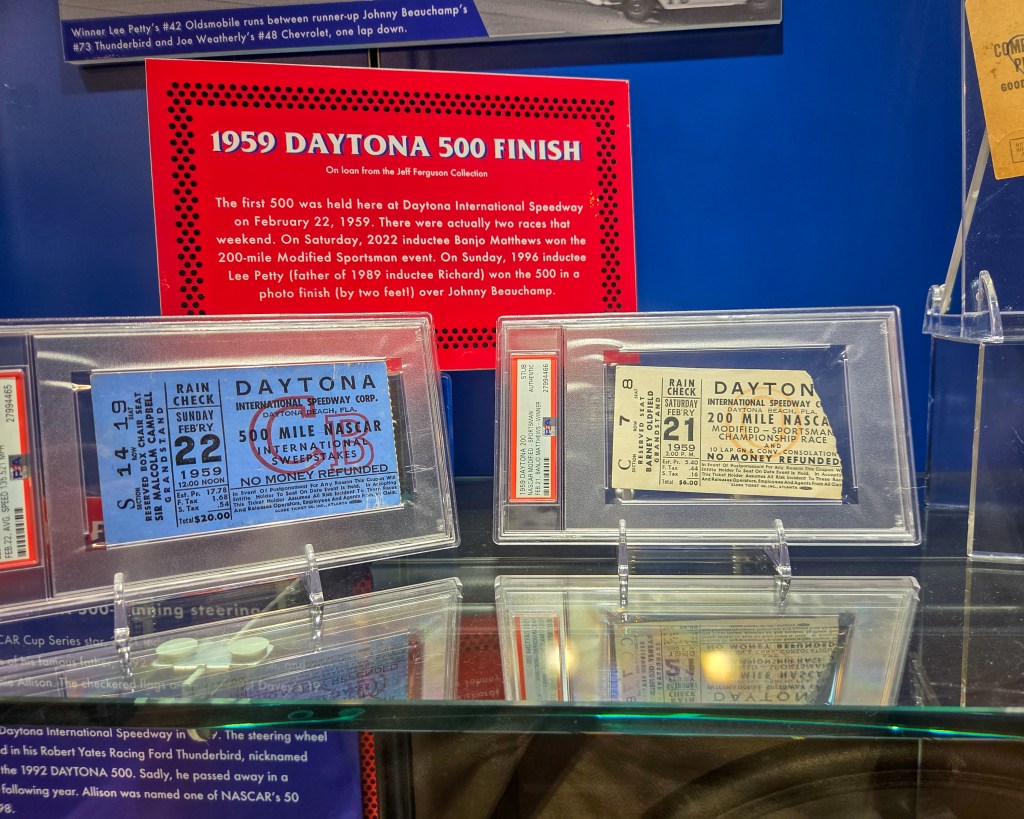 Museum exhibit case displaying framed documents, certificates, and a large red informational panel about the 1995 Daytona 500 finish, including race results and memorabilia.