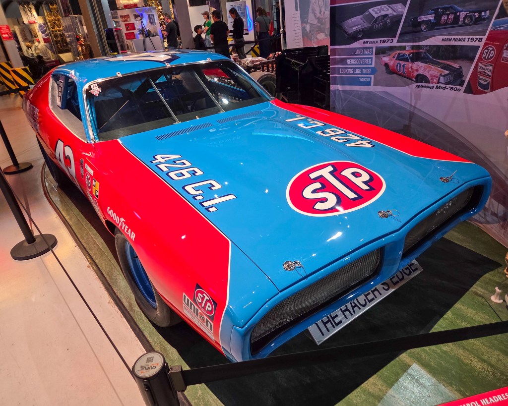 1972 Richard Petty race car painted in bright blue with a large red hood section featuring a circular red STP logo, shown from a front three-quarter angle on indoor display with license plate visible.